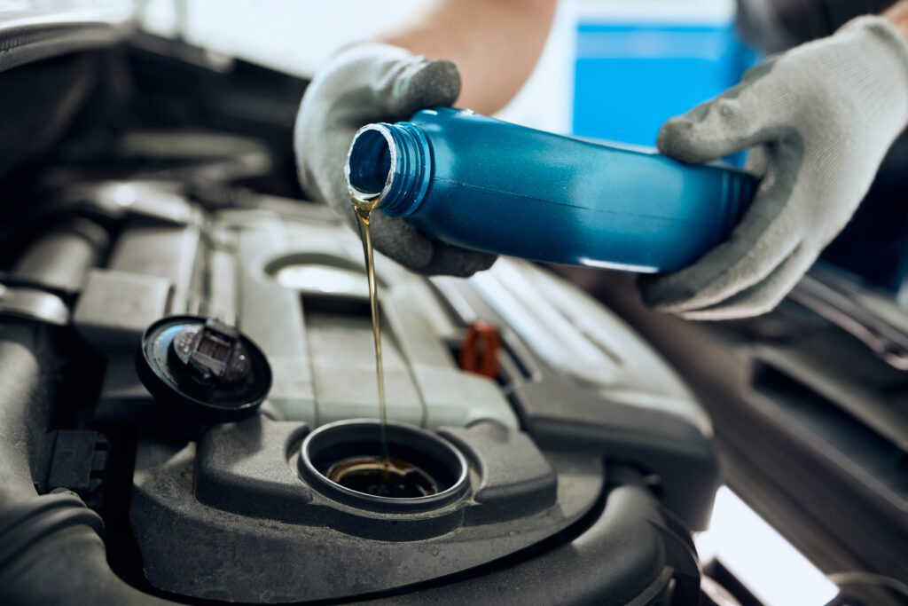 Close-up of repairman changing engine oil while working at car workshop.